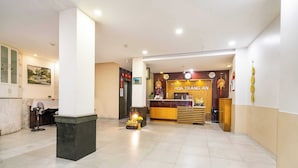 Een hotel receptie met een receptiebalie, een klok en een klein altaar met offers.
