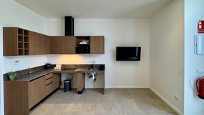 A modern kitchen with wooden cabinets, a microwave, a sink, and a flat-screen TV. - Plaza Tower Loft 01 (Valencia)