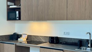 Una cocina moderna con armarios de madera, microondas integrado, cafetera y tostadora.
