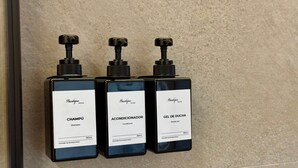 Tres botellas negras con etiquetas blancas sobre una pared.
