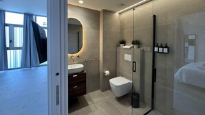Un baño moderno con cabina de ducha de vidrio, un lavamanos y un inodoro.