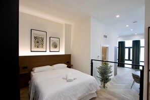Una habitación de hotel moderna con una cama grande, una mesita de noche pequeña, una planta en maceta y vistas al balcón.