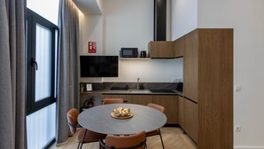 A modern kitchen with a dining table, chairs, a microwave, and a TV. - One Tower Loft 08 (Valencia)