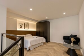 Un dormitorio moderno con una cama, una mesita redonda y un sofá negro.