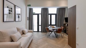 A modern living room with a sofa, a dining table with chairs, and a TV on a stand. - One Tower Loft 08 (Valencia)