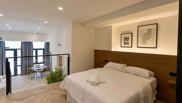 A hotel room with a large bed, a dining area with a table and chairs, and a balcony with a view. - One Tower Loft 08 (Valencia)