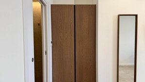 A room with a wooden wardrobe, a door, and a mirror on the wall.