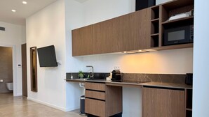 A modern kitchen with wooden cabinets, a built-in microwave, and a flat-screen TV mounted on the wall.
