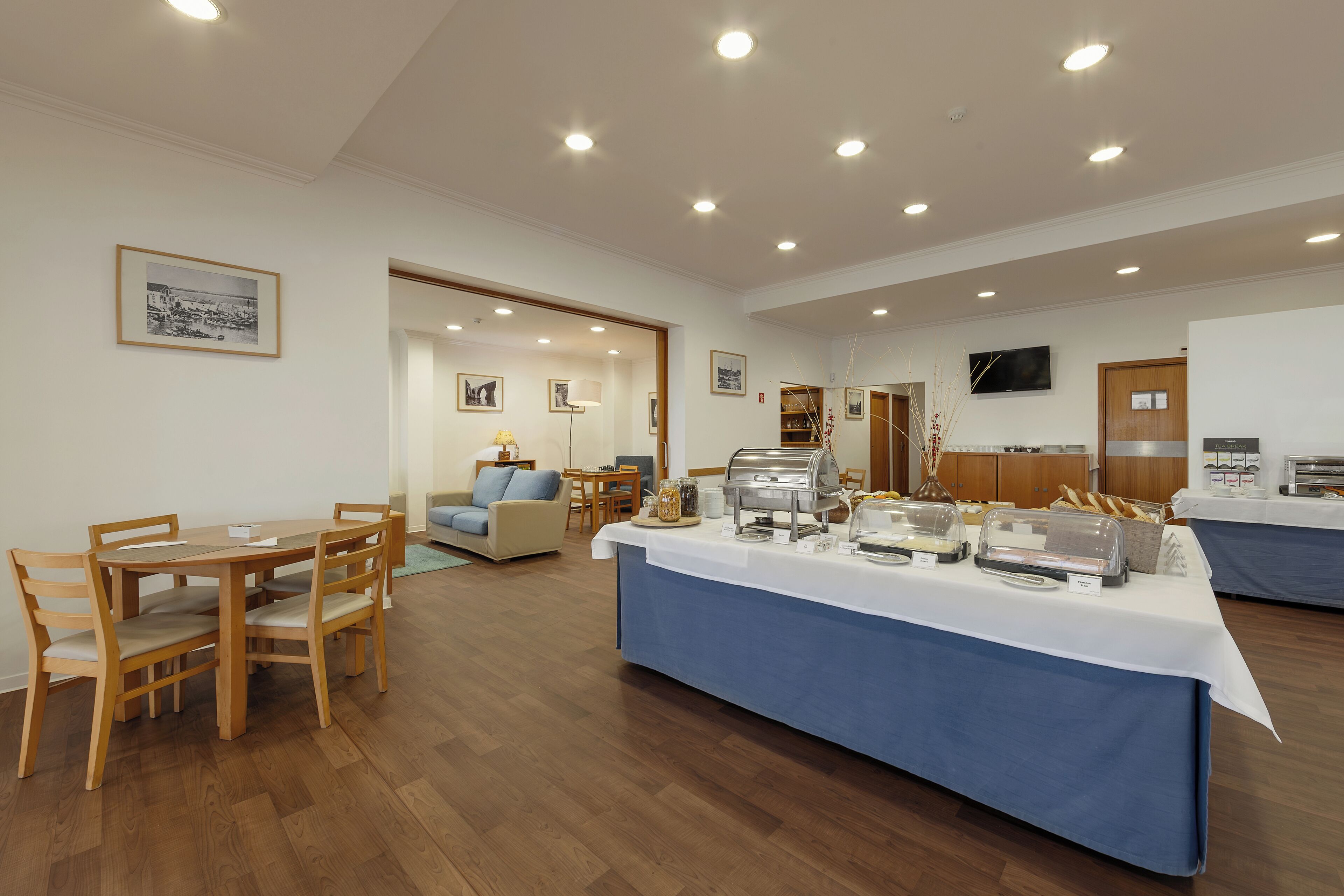 Un espace repas avec une table de buffet, des chaises en bois et un canapé en arrière-plan.