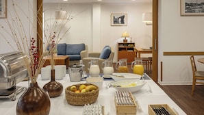 Ein reichhaltiges Frühstücksbuffet mit verschiedenen Speisen, Getränken und einem Essbereich mit Sofa und Tisch.