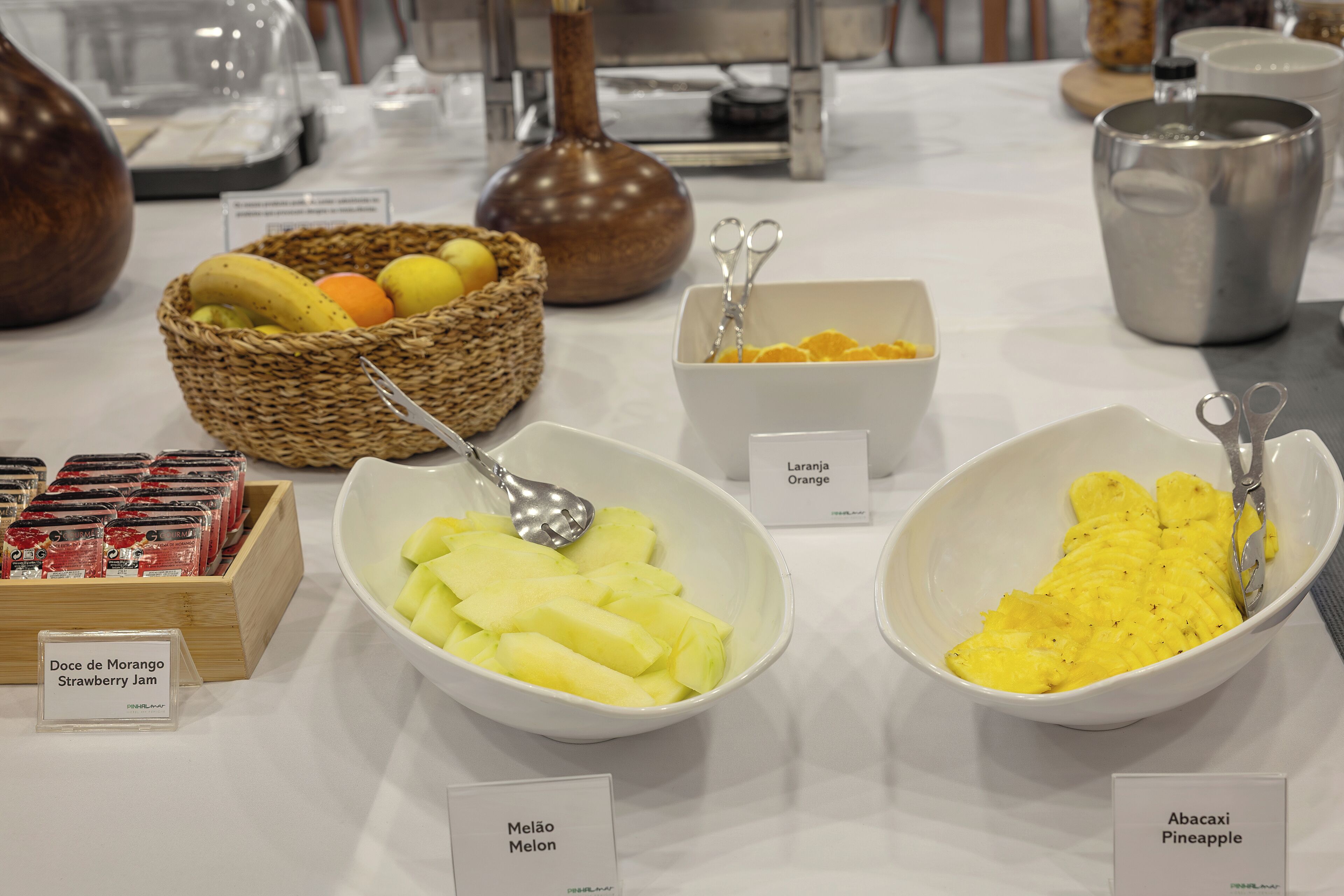 Una mesa de bufé con diversas opciones de comida, incluyendo naranja, piña y melón.