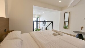 Moderni hotellihuone, jossa on suuri sänky, pieni pöytä ja peili.