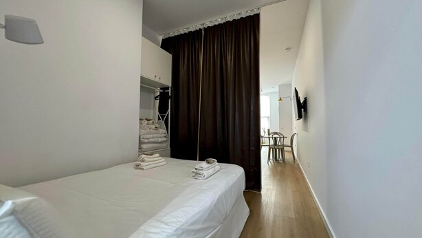Una camera d'albergo con un letto, un armadio, una scrivania e una televisione.