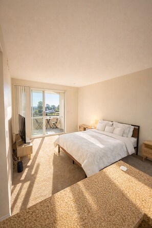 A bedroom with a bed, a TV, a desk, and a balcony with outdoor furniture. - Cozy 1-bedroom apartment in Marina Del Rey - Venice (Marina del Rey)