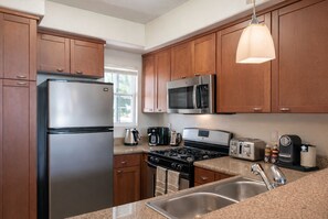 A modern kitchen with wooden cabinets, stainless steel appliances, a gas stove, a microwave, a toaster, and a sink. - Cozy 1-bedroom apartment in Marina Del Rey - Venice (Marina del Rey)