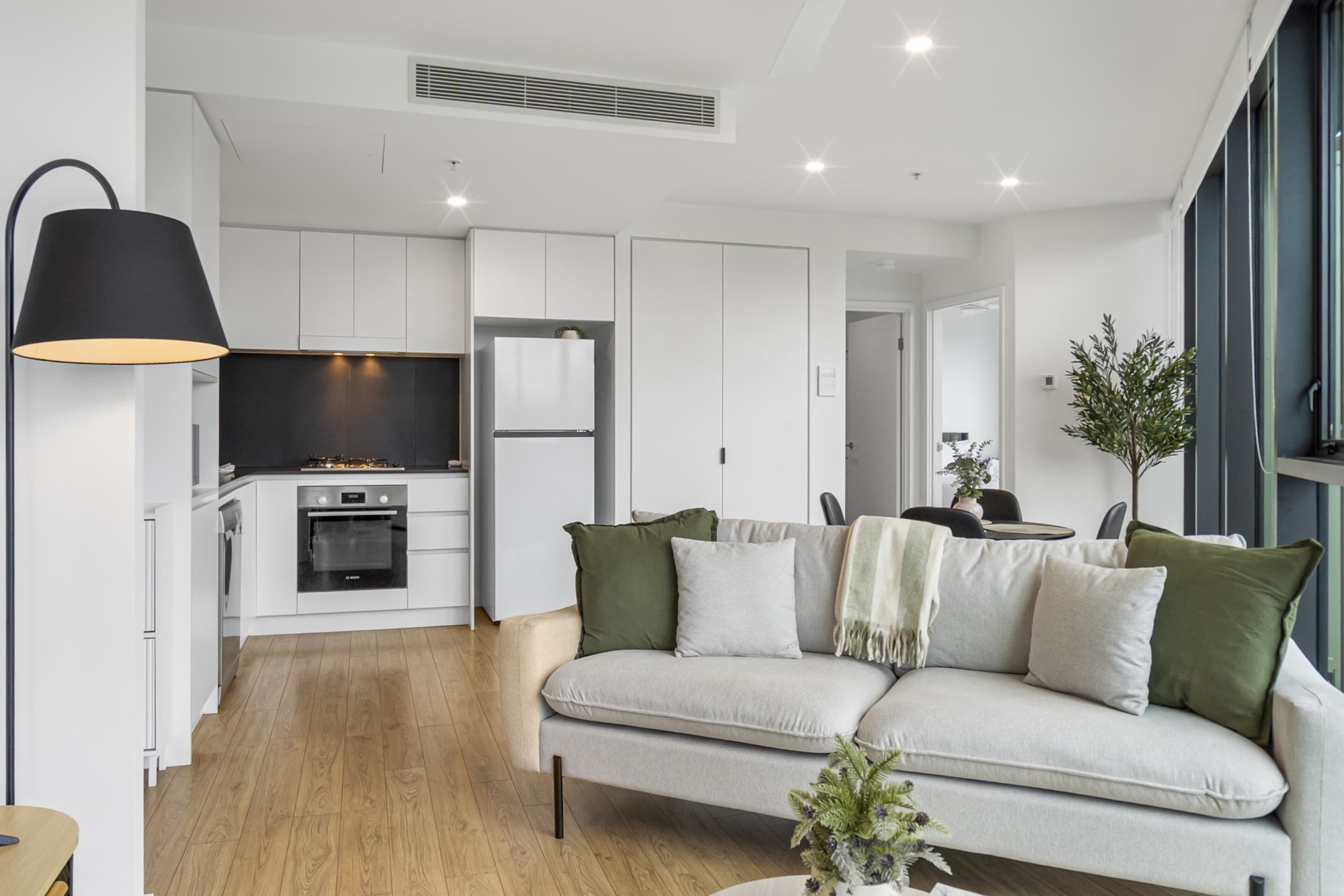 A modern kitchen with white cabinets, a black oven, and a built-in TV.