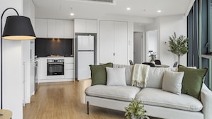 A modern kitchen with white cabinets, a black oven, and a built-in TV. - Stylish 1-bed Apartment in South Brisbane (Brisbane)