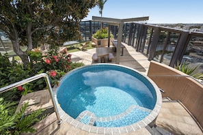 A rooftop pool with a glass balustrade, surrounded by greenery and a seating area. - Stylish 1-bed Apartment in South Brisbane (Brisbane)