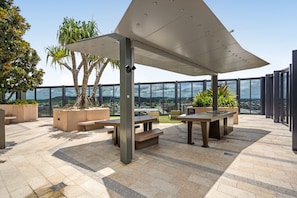 An outdoor terrace with seating, planters, and a view of the cityscape. - Stylish 1-bed Apartment in South Brisbane (Brisbane)