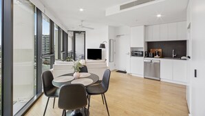 A modern apartment with a dining area, kitchen, and a large window overlooking a cityscape. - Stylish 1-bed Apartment in South Brisbane (Brisbane)