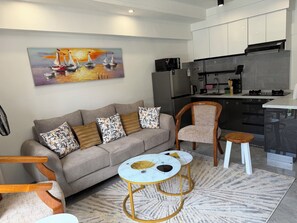 A modern living room with a sofa, coffee table, and a painting of sailboats. - One bedroom in Lavington, Nairobi (Nairobi)