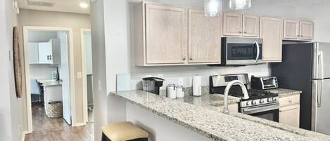 A modern kitchen with granite countertops, stainless steel appliances, and wooden cabinets.