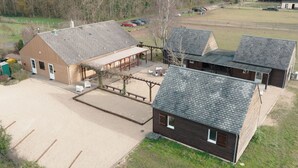 Suuri rakennus, jossa on useita huoneita, katettu ulkoalue istumista varten ja aidattu pysäköintialue.