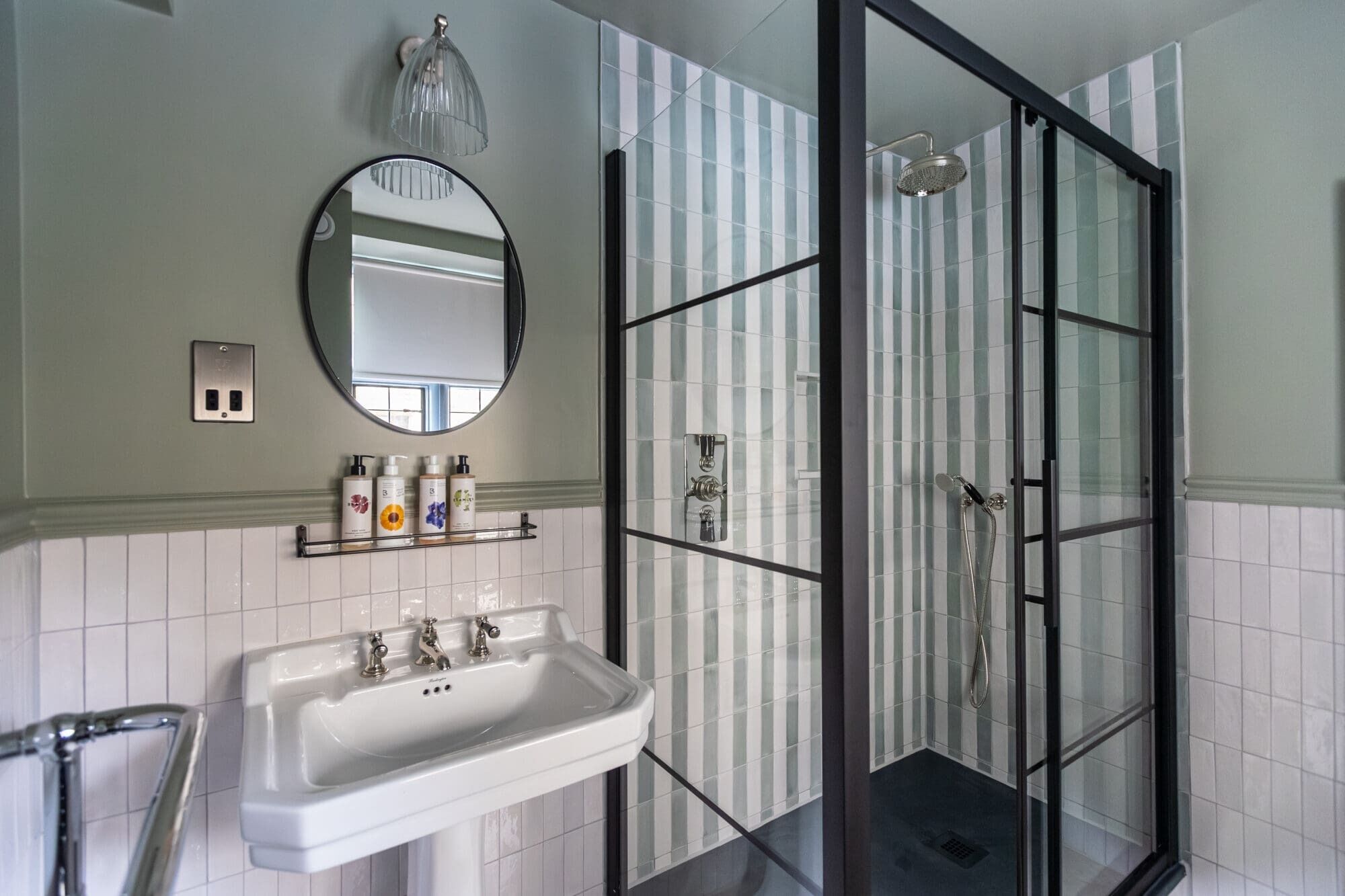 Un baño con lavamanos blanco, un espejo y una cabina de ducha de vidrio.