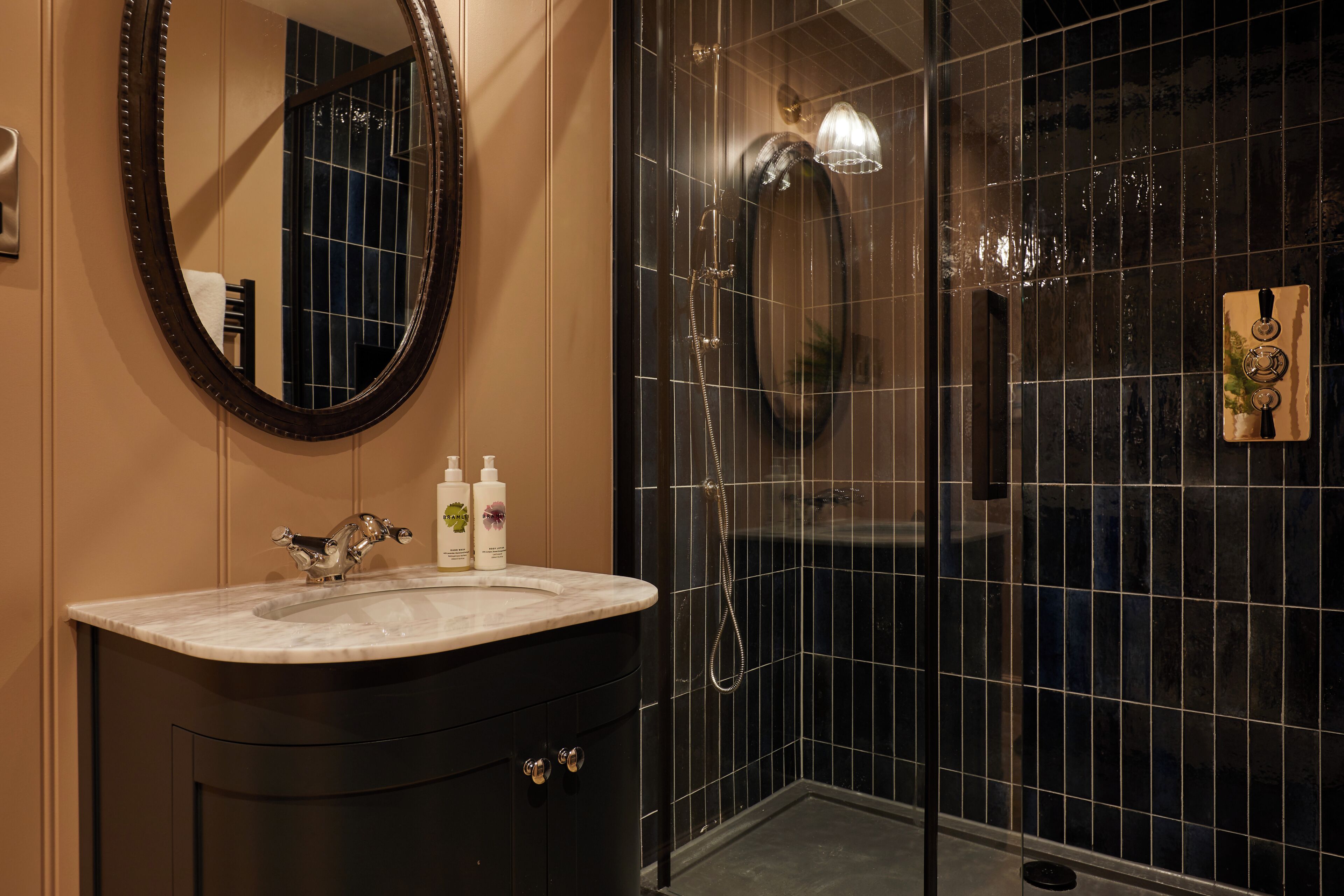 Une salle de bain avec un lavabo en marbre, un miroir et une douche à parois de verre.