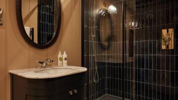 Une salle de bain avec un lavabo en marbre, un miroir et une douche à parois de verre.