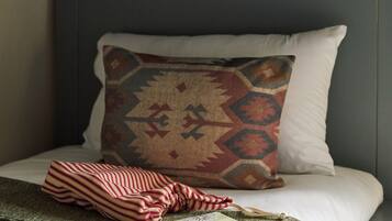 A bed with a patterned pillow, a striped blanket, and a book.