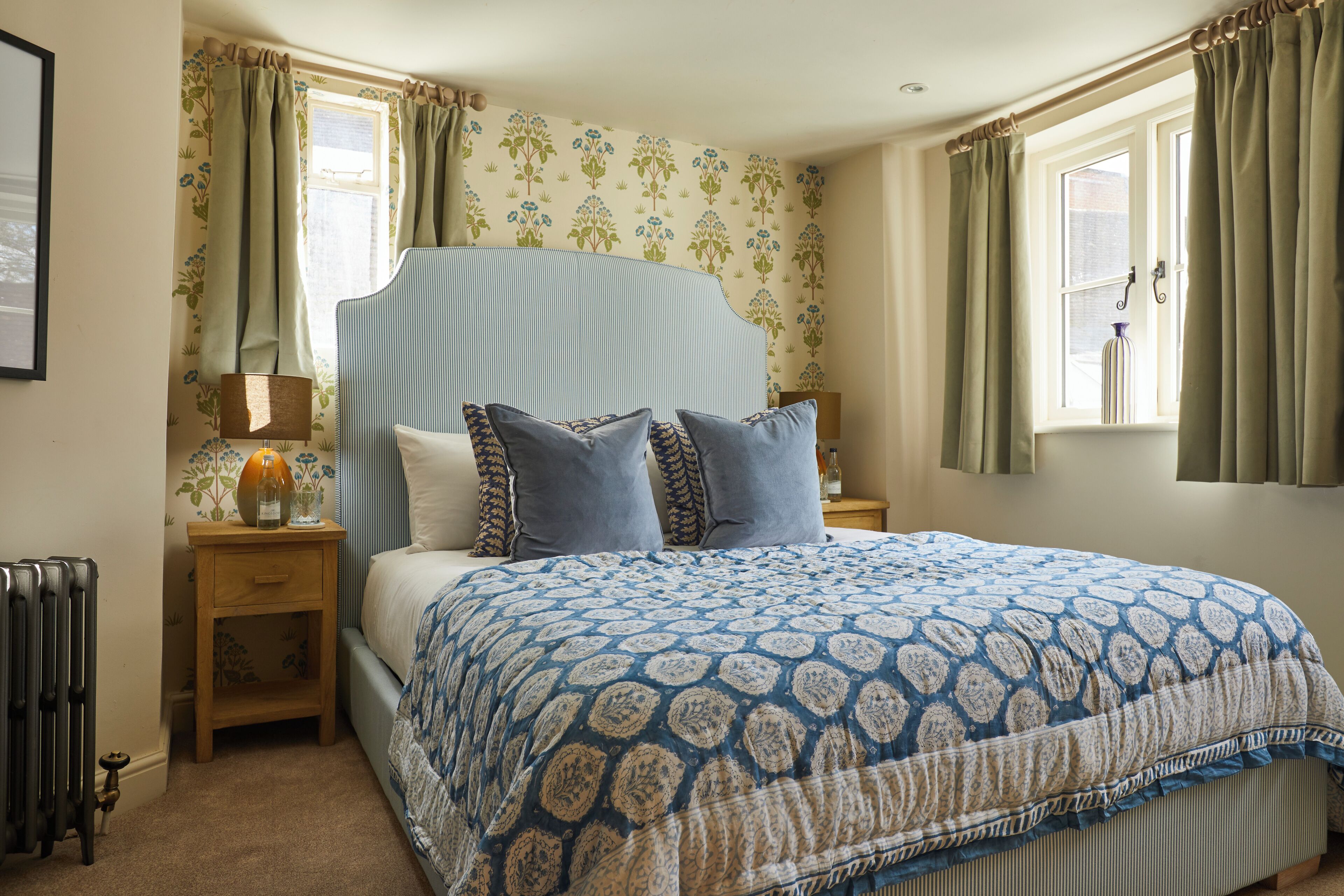 A bedroom with a bed, a nightstand, a lamp, and a window with curtains.