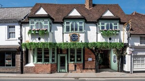 A traditional pub with a green door, white walls, and flower boxes above the windows. - The Bull on Bell Street (Henley-on-Thames)