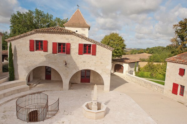 A building with red shutters, a central courtyard, and a tower. - Gîte la Maison du Randonneur (Castelnau-sur-l'Auvignon)