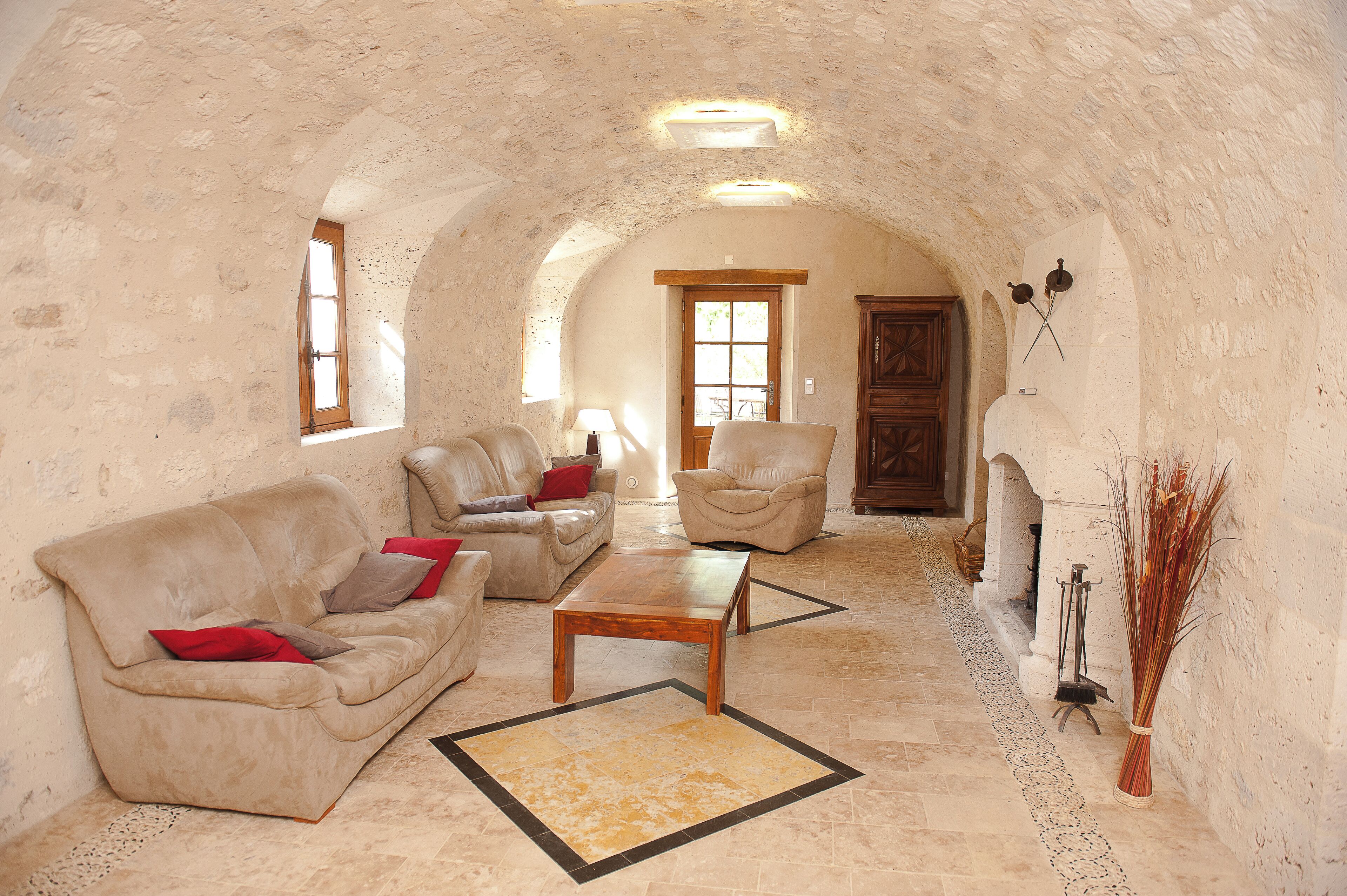 A cozy living room with a stone archway, leather sofas, a wooden coffee table, and a decorative vase.