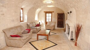 Un salón acogedor con un arco de piedra, sofás de cuero, una mesa de centro de madera y un jarrón decorativo.
