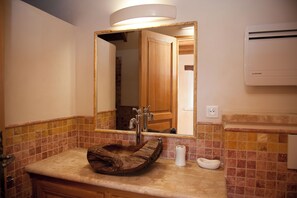 A bathroom with a wooden sink, a mirror, a towel, and a wall-mounted air conditioner. - Gîte la Maison du Randonneur (Castelnau-sur-l'Auvignon)