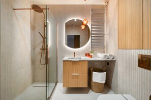 A modern bathroom with a glass shower enclosure, a wooden vanity, a round mirror, and a towel rack. - Luxurious Apartment in Miedzyzdroje, SPA Zone (Międzyzdroje)