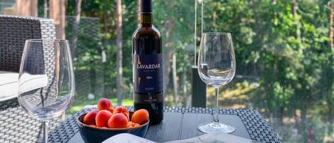 A bottle of Lavardar 2020 wine, a bowl of fruit, and two wine glasses on a table with a magazine.