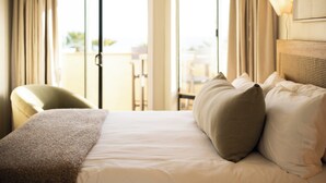 Een hotelkamer met een bed, een stoel en een balkon met uitzicht.