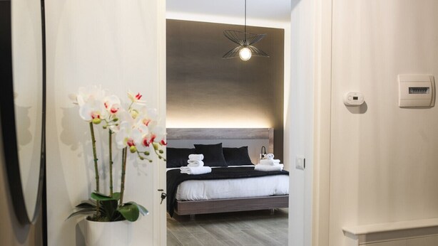 Een moderne hotelkamer met een bed, een nachtkastje, een potorkidee en een plafondlamp.