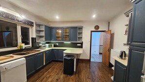 Eine moderne Küche mit dunkelblauen Schränken, einer weißen Arbeitsplatte und Holzboden.
