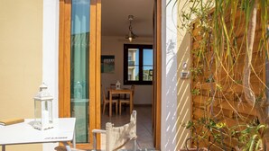 Eine Terrasse mit Tisch und Stühlen, einer Laterne und einem Holzzaun mit Pflanzen.