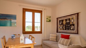Ein Zimmer mit einem Holztisch, einem beigen Sofa und einem großen Fenster mit Vorhängen.