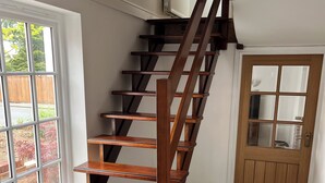 Een houten trap met een leuning, die leidt naar een verdieping.