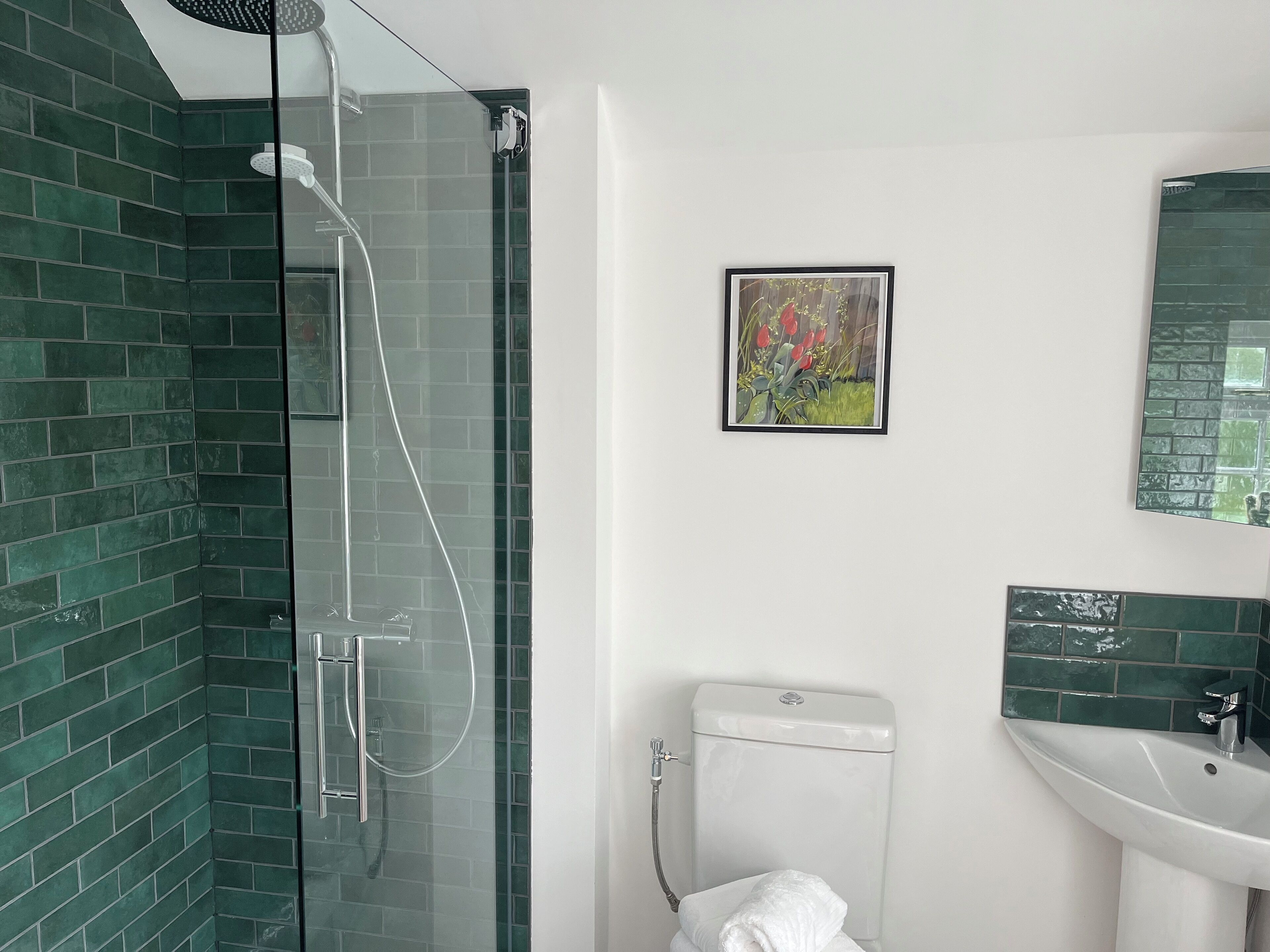 A bathroom with a glass-enclosed shower, a toilet, and a sink.