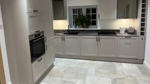 Een moderne keuken met witte kasten, een inbouwoven en een spoelbak.