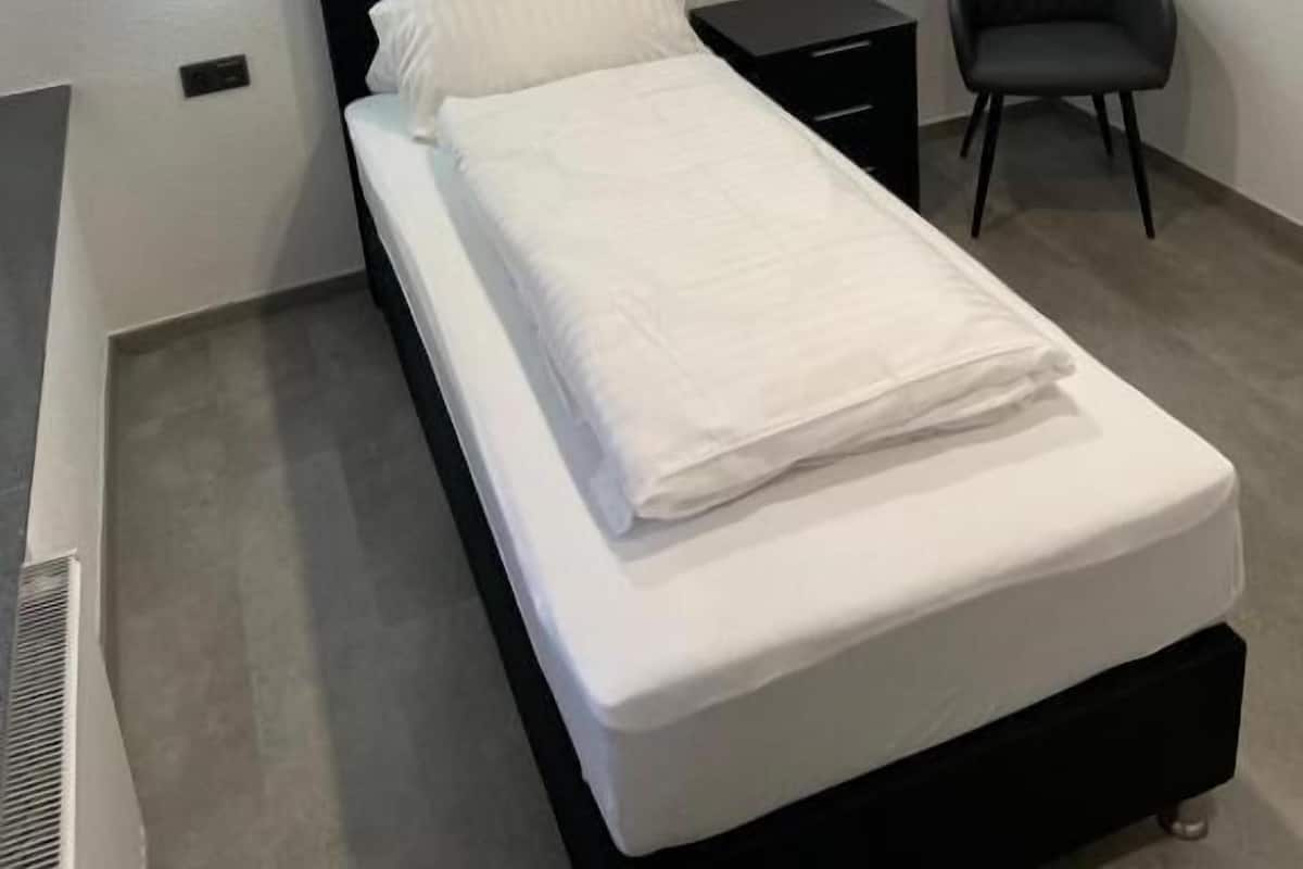 Et moderne soveværelse med en enkelt seng, sengeborde og en stol.