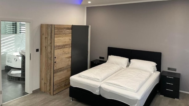 A modern bedroom with a bed, bedside tables, and a wardrobe. - Hotel Anker  (Linden)