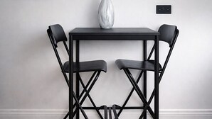 Een eetruimte met een tafel en vier stoelen, kunstwerken aan de muur en een vaas met witte bloemen.